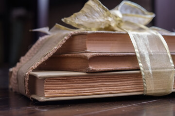 Well read and worn out books wrapped with a hemp and gold ribbon on an antique wooden floor