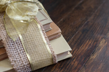 Well read and worn out books wrapped with a hemp and gold ribbon on an antique wooden floor