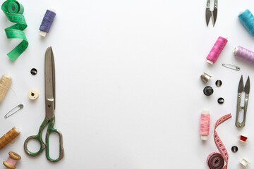 Flat lay composition with scissors and other sewing accessories on white background. Space for text