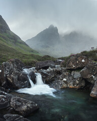 Morning view of river with waterfall and cloud covered mountain range. Scenic summer landscape with trickling waterfall in the morning. Bla Bheinn, Isle of Skye, Scottish Highlands, UK.
