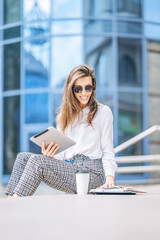 Young business lady working on the tablet outdoors near business center.