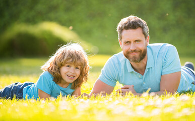 happy family portrait of father and son kid relax in summer park green grass, summer relax