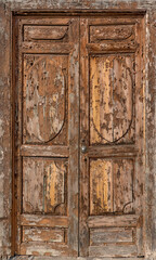 Alte, stark verwitterte braune Tür aus Holz im Holzrahmen