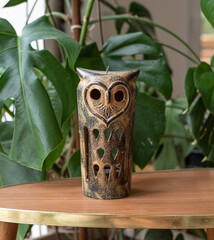 Mid-century modern owl pottery on a wooden table with plants in the background
