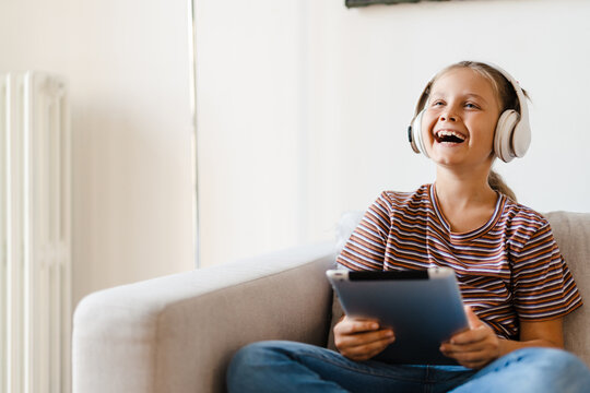 White girl in headphones laughing and using tablet computer