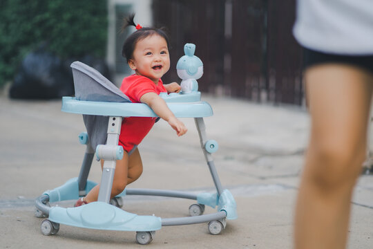 child in happy time child running with mom in outdoor at road village to practice balance walk in development according to the age of the child on Baby car to help practice walking