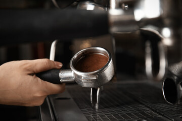 Barista making espresso using professional coffee machine, closeup