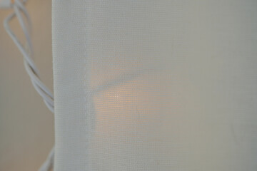 Horizontal image of Soft linen curtains covering soft white  lights inside a home making for a...