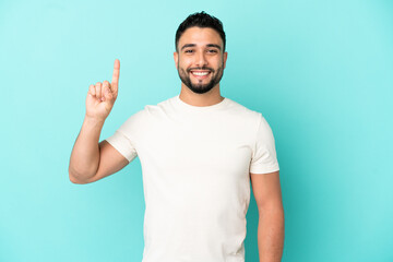Young arab man isolated on blue background pointing up a great idea