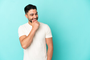 Young arab man isolated on blue background looking to the side and smiling