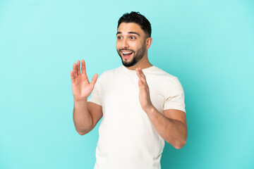 Young arab man isolated on blue background with surprise facial expression