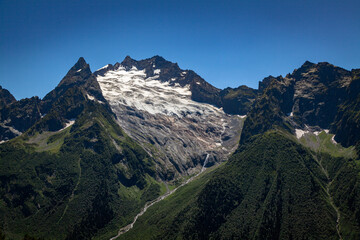 snowy rocky mountains with forest slopes