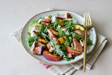 Salad with peaches, arugula, cheese and jamon. Healthy eating.