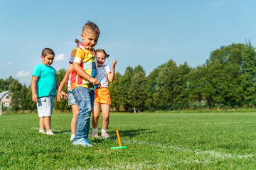 Obraz premium group of small happy preschoolers throw rings running in the park on a sunny summer day. Outdoor games in the fresh air. A fun childhood. A strong friendship. Children Protection Day.