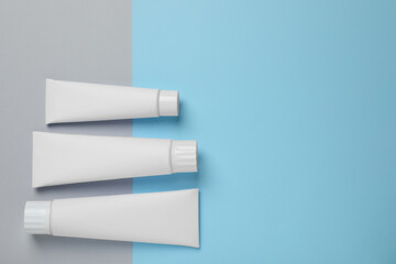 Blank tubes of toothpaste on color background, flat lay. Space for text