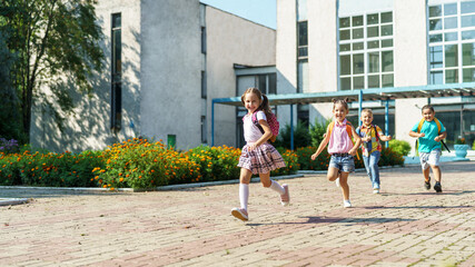 group of school children with backpacks run out of school, after the end of classes. Classmates, school friends. The beginning of holidays. The end of quarantine. Back to school.