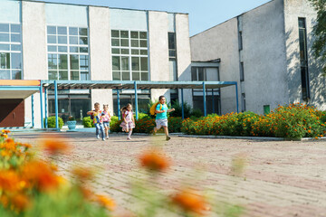 group of school children with backpacks run out of school, after the end of classes. Classmates, school friends. The beginning of holidays. The end of quarantine. Back to school.