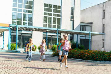 group of school children with backpacks run out of school, after the end of classes. Classmates, school friends. The beginning of holidays. The end of quarantine. Back to school.