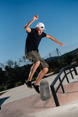 Young man jumping a railing on a skateboard.