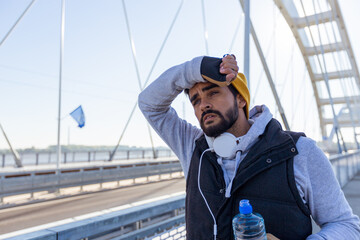 Male runner resting after morning run in urban environment