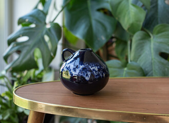 Mid-century modern pottery - jug on a wooden table with plants in the background - vintage home decor