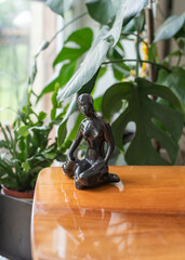 Mid-century modern ceramic figurine, black nude - on a wooden table with plants and widow in the background