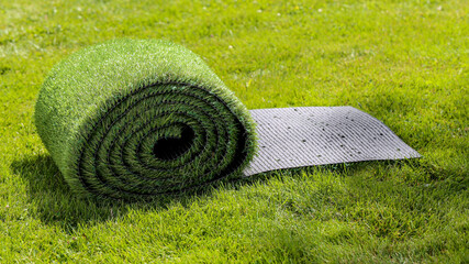 rouleau de pelouse synthétique sur pelouse naturelle - obrazy, fototapety, plakaty