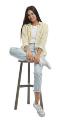 Beautiful young woman sitting on stool against white background