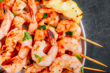 Grilled Lemon Shrimp Skewers in plate on gray stone background close-up.