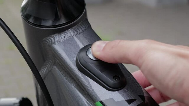 Turning on an electric bicycle, pressing power button on ebike frame. Environmentally friendly means of transport.