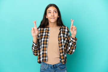 Young French woman isolated on blue background with fingers crossing and wishing the best