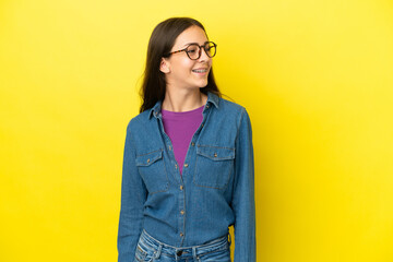 Young French woman isolated on yellow background looking side