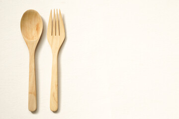 top view of wooden cutlery placed on beige background with copy space.