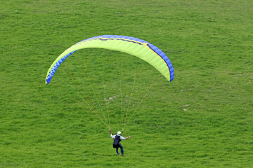 Paraglider pilot landing in a field