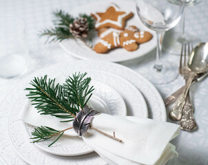 Christmas table set with white textured plates, vintage cutlery and traditional christmas biscuits