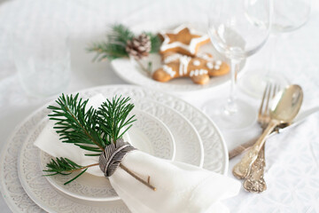 Christmas table set with white textured plates, vintage cutlery and traditional christmas biscuits