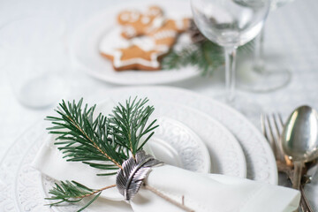 Obraz na płótnie Canvas Christmas table set with white textured plates, vintage cutlery and traditional christmas biscuits