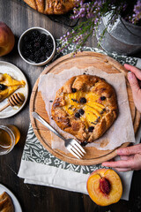 French galette with peaches, blackberries, mascarpone, natural honey and lavender on baking paper.