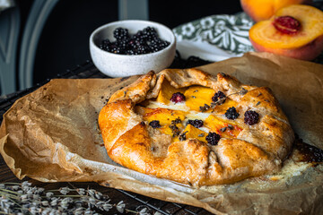 French galette with peaches, blackberries, mascarpone, natural honey and lavender on baking paper.
