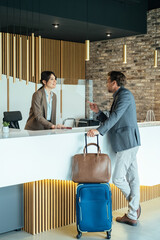 Female Hotel Receptionist Assisting Businessman for Checking In.
Business man with luggage talking...