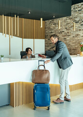 Handsome Business Man Checking In at Hotel. 
Businessman with passport and suitcase arriving in...