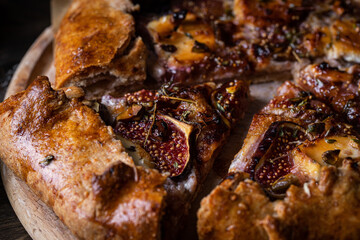 French galette with figs, goat cheese, pistachios and natural honey on baking paper on wooden table. 