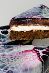 Close-up mousse cake covered black, red and white mirror glaze. French dessert. Frozen mirror icing on the cake. Baking and confectionery concept.