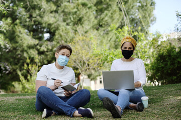 Two elegant woman put on protective face mask outdoors. COVID-19 quarantine, travel