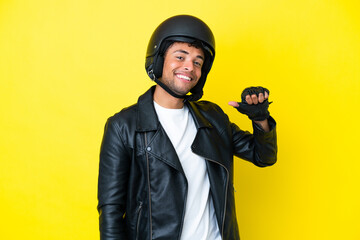 Young Brazilian man with a motorcycle helmet isolated on yellow background proud and self-satisfied