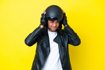 Young Brazilian man with a motorcycle helmet isolated on yellow background frustrated and covering ears