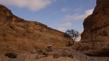 Fototapeta premium Rock cairns packed on a rock in the riverbed of the Sesriem Canyon, a popular hiking trail at Sesriem, Namibia