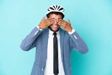 Young business Brazilian man with bike helmet isolated on blue background covering eyes by hands