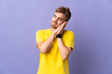 Young handsome blonde man isolated on purple background making sleep gesture in dorable expression