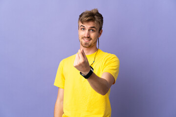 Young handsome blonde man isolated on purple background making money gesture